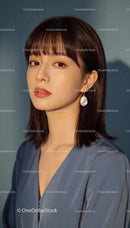 Thoughtful young woman in blue blouse with pearl earring