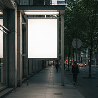 Empty illuminated billboard on urban street in evening