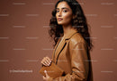 Elegant Female Model in Leather Jacket Holding Clutch Against Brown Background