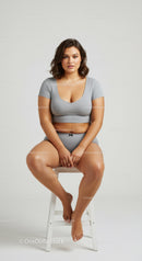 Confident Young Woman Sitting on Stool Wearing Casual Gray Outfit