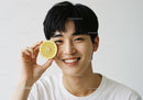 Young Man Smiling with Lemon Slice in Bright Minimalist Portrait