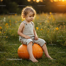 Toddler Sitting on Pumpkin in Sunny Meadow at Sunset