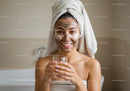Young Woman Relaxing with Facial Mask and Drinking Glass of Water