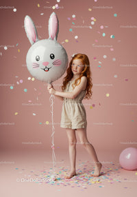 Redheaded girl holding bunny balloon with confetti