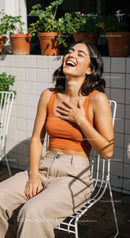 Joyful Woman in Orange Top Relaxing on Outdoor Terrace