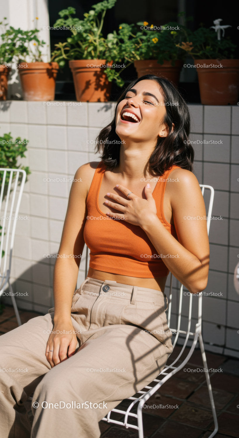 Joyful Woman in Orange Top Relaxing on Outdoor Terrace