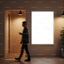 Man walking past illuminated blank poster in modern interior