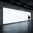 Blurred man walking past large glowing billboard