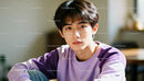 Young man in purple sweatshirt with thoughtful expression