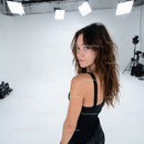 Young woman with curly hair in black dress standing in studio