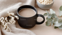 Black Coffee Mug with Eucalyptus and White Flowers in Cozy Setting