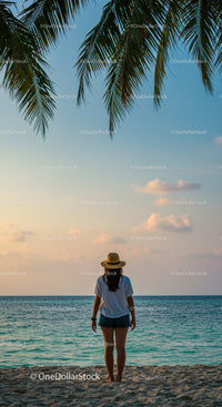 Woman Standing Alone on Beach at Sunset with Palm Trees and Ocean View