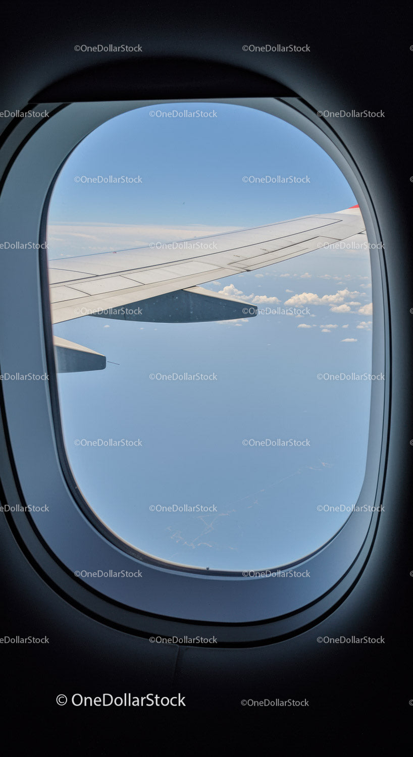 View of Airplane Wing and Blue Sky from Passenger Window