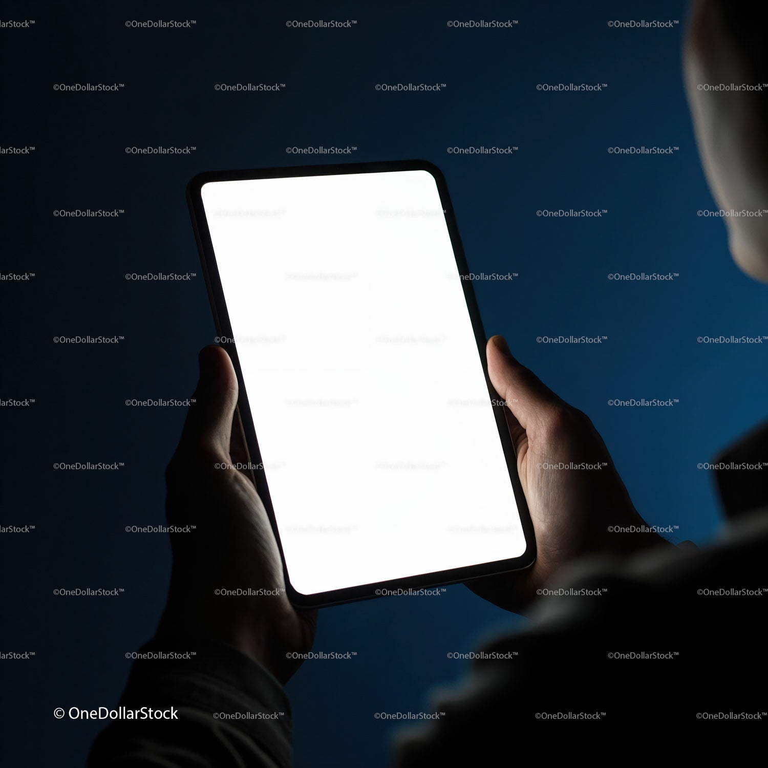Osoba trzymająca tablet z pustym, jasnym ekranem w ciemnym pokoju