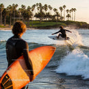 Surfer catching a wave near palm tree coastline