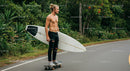 Young Man on Skateboard Holding Surfboard in Nature Setting