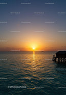 Sunset Over Calm Ocean with Pier and Boat Silhouette