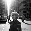 Elderly Woman in Busy City Street Surrounded by Vintage Cars