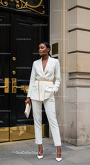 Elegant woman in white suit with gold chain belt outdoors