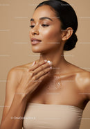 Elegant woman with glowing skin applying moisturizer on her shoulder