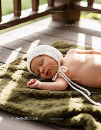 Peaceful newborn baby sleeping on textured green blanket