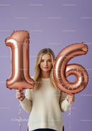 Young woman celebrating sixteenth birthday with balloons