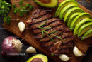 Grilled Steak with Avocado and Fresh Herbs on Wooden Cutting Board