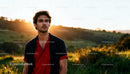 Young man standing outdoors with sunset in background