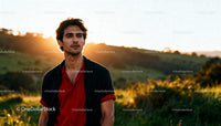 Young man standing outdoors with sunset in background