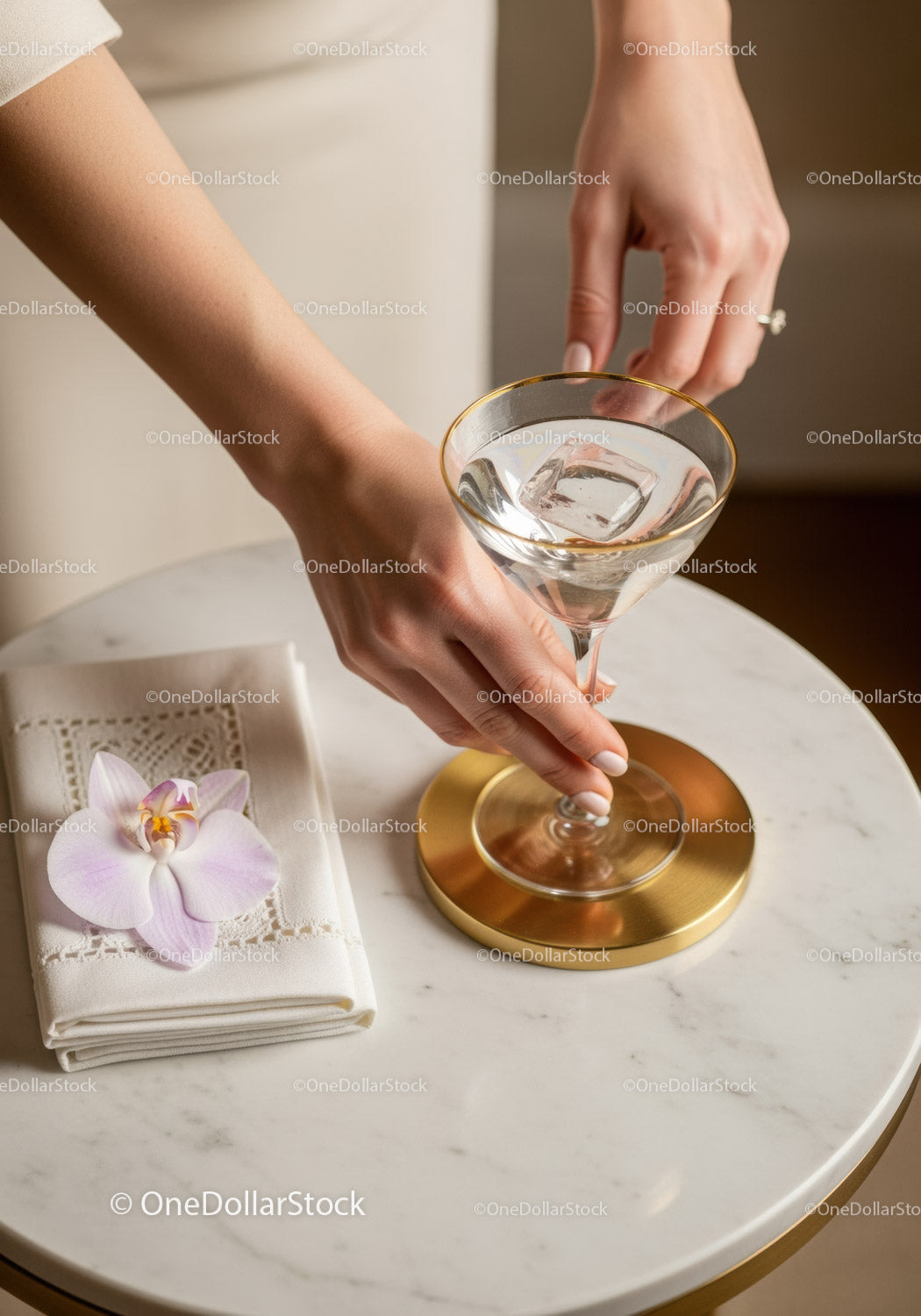 Elegant Woman Holding Martini Glass with Ice on Marble Table