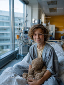 Young Boy Sitting in Hospital Bed Smiling with Teddy Bear