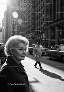 Elderly Woman in Busy City Street Surrounded by Vintage Cars