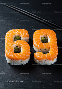 Salmon sushi rolls shaped as number sixty nine with chopsticks