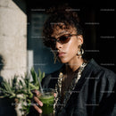 Stylish Woman with Sunglasses Holding Green Drink in Urban Setting