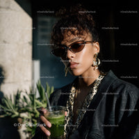 Stylish Woman with Sunglasses Holding Green Drink in Urban Setting