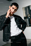 Young man in denim jacket posing thoughtfully indoors