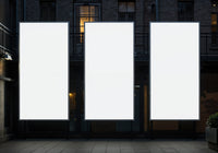 Three Blank Vertical Billboards Against Urban Building Facade