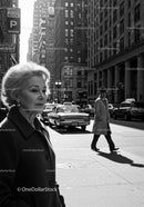 Elderly Woman in Busy City Street Surrounded by Vintage Cars