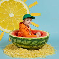 Boy sitting inside a watermelon bowl with sun decor