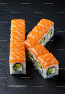 Fresh salmon sushi rolls with avocado on black plate