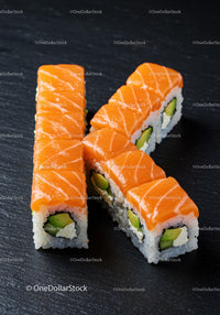 Fresh salmon sushi rolls with avocado on black plate
