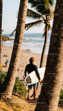 Surfer walking down beach path under palm trees