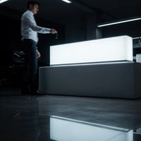 Man Holding Key Near Illuminated Modern Desk in Dark Room