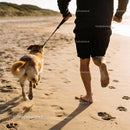 Man Running Barefoot with Dog on Beach at Sunset