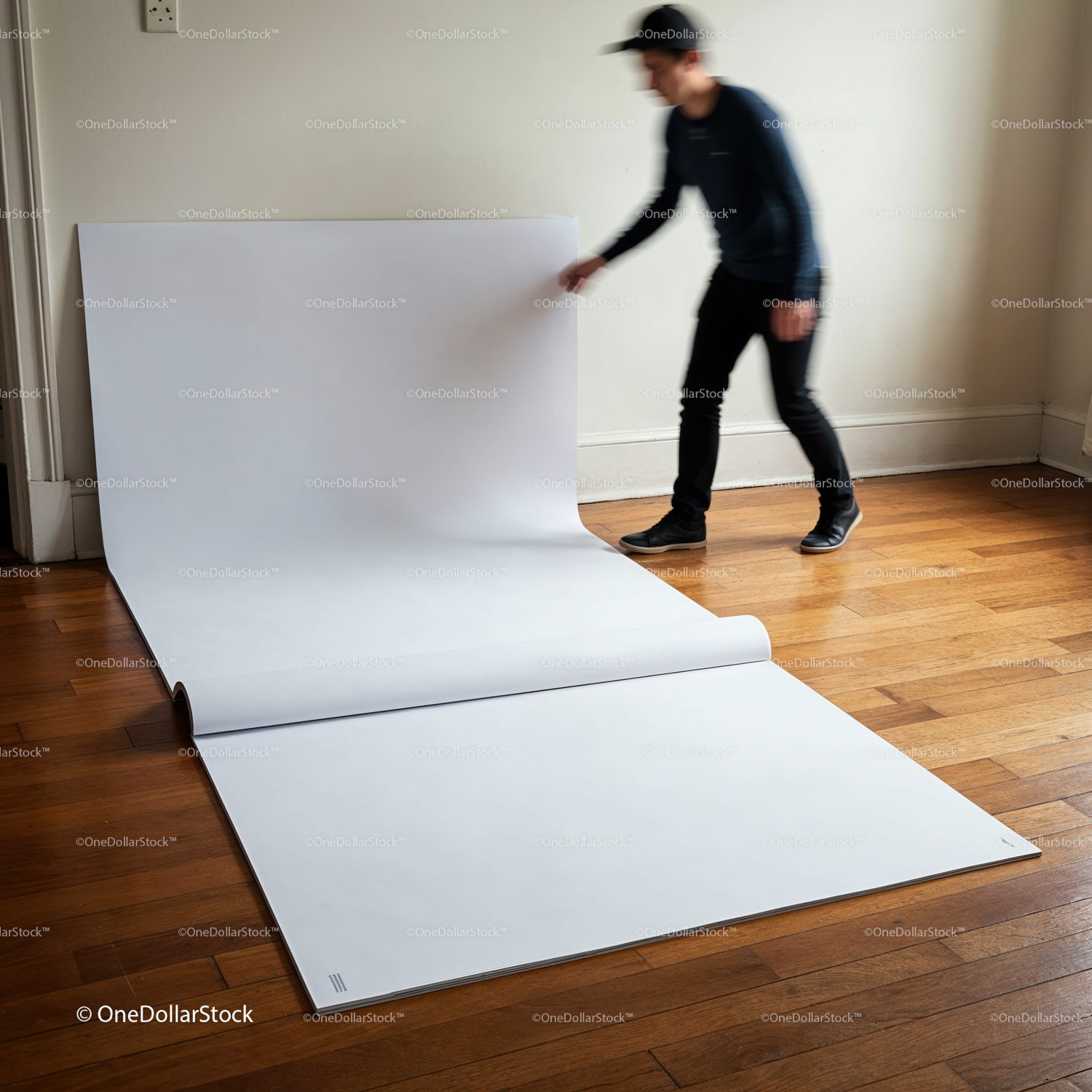 Person Unrolling Large White Sheet on Wooden Floor