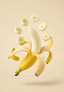 Peeled banana with hovering banana slices on beige background