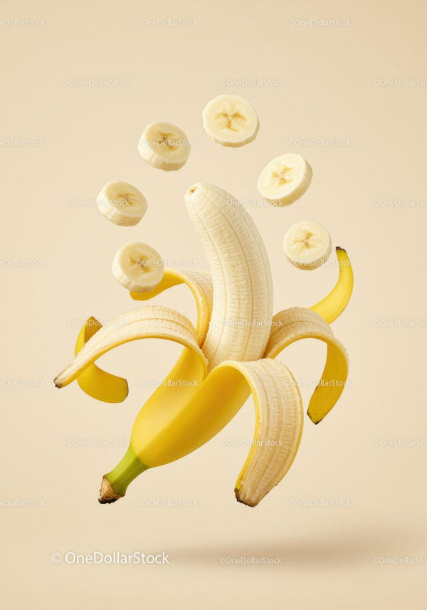 Peeled banana with hovering banana slices on beige background