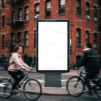 Urban street cyclists passing blank billboard in city