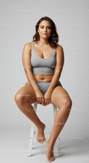 Confident Young Woman Sitting in Grey Sportswear in Studio