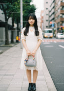 Elegant Woman in White Lace Dress Standing on City Sidewalk
